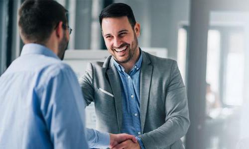 MBA graduate smiling and shaking hands after earning leadership position 